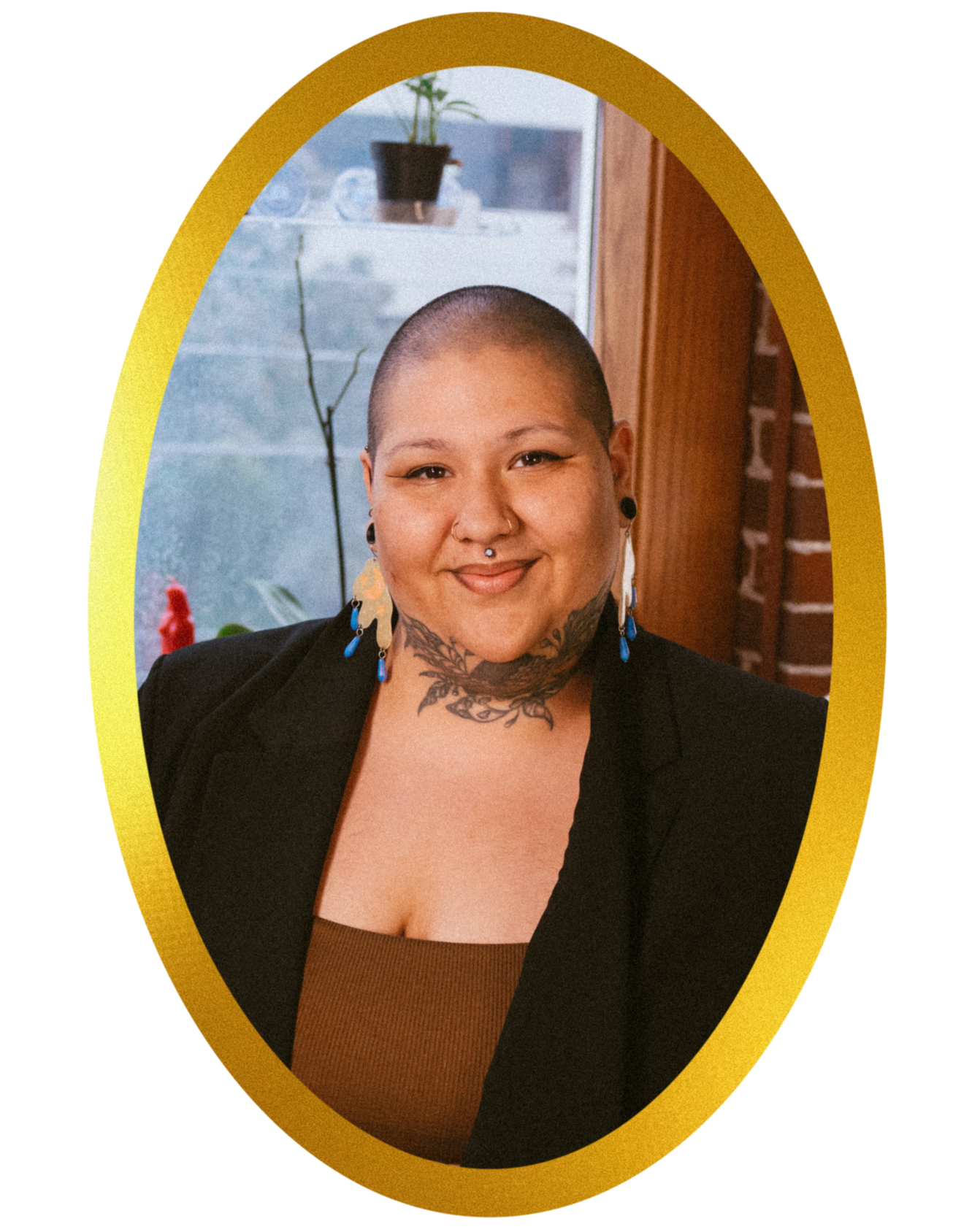 A photograph of artist Toni PNW, a person with a shaved head and a black and grey neck tattoo of a seashell and vines. She is wearing a black blazer with a brown top underneath and abstract shaped, purple earrings. The photo is in a gold, oval frame.